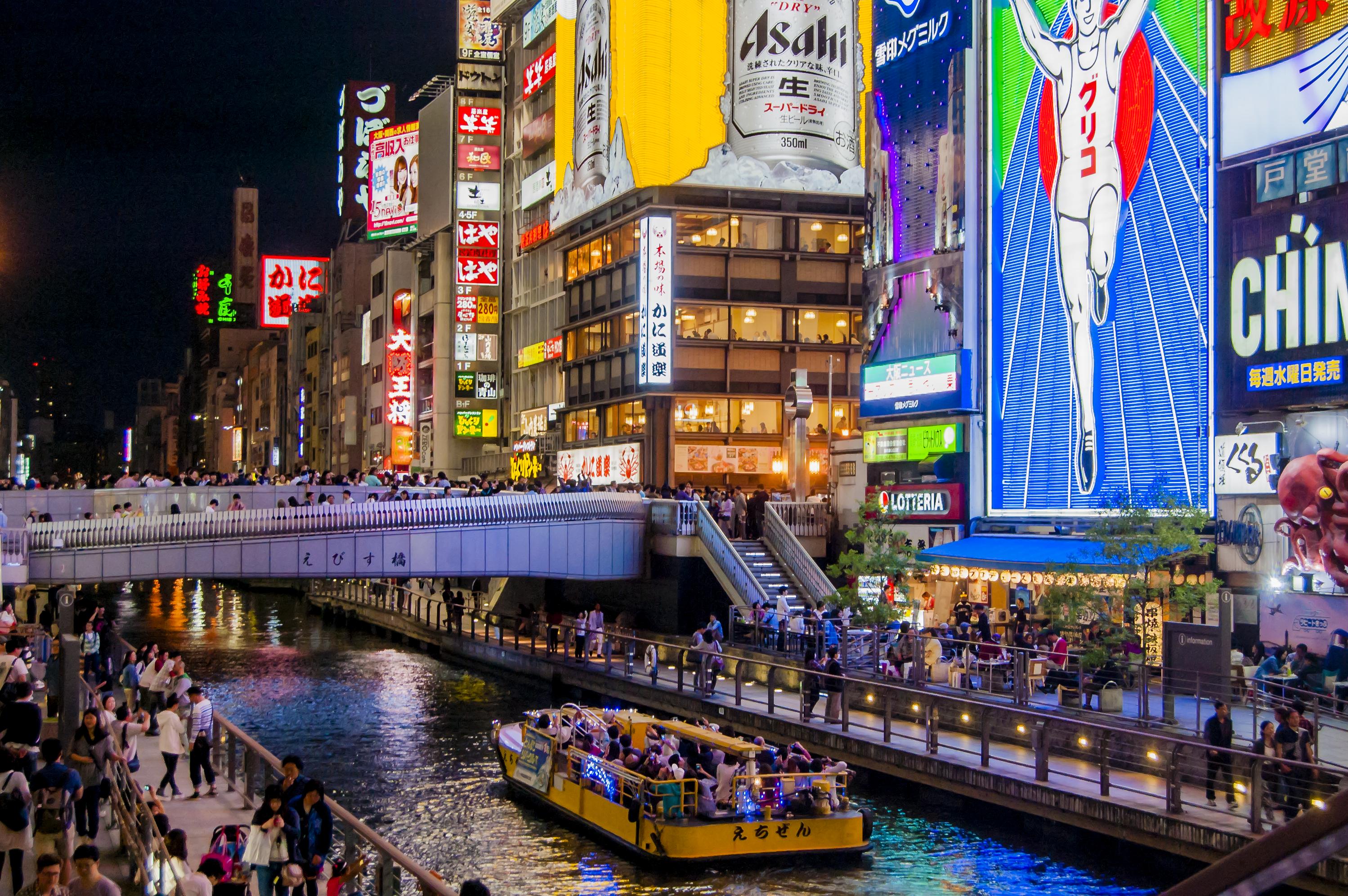 Cruise boat on the Dotonbori river at night beside the Glico sign, Osaka, Japan