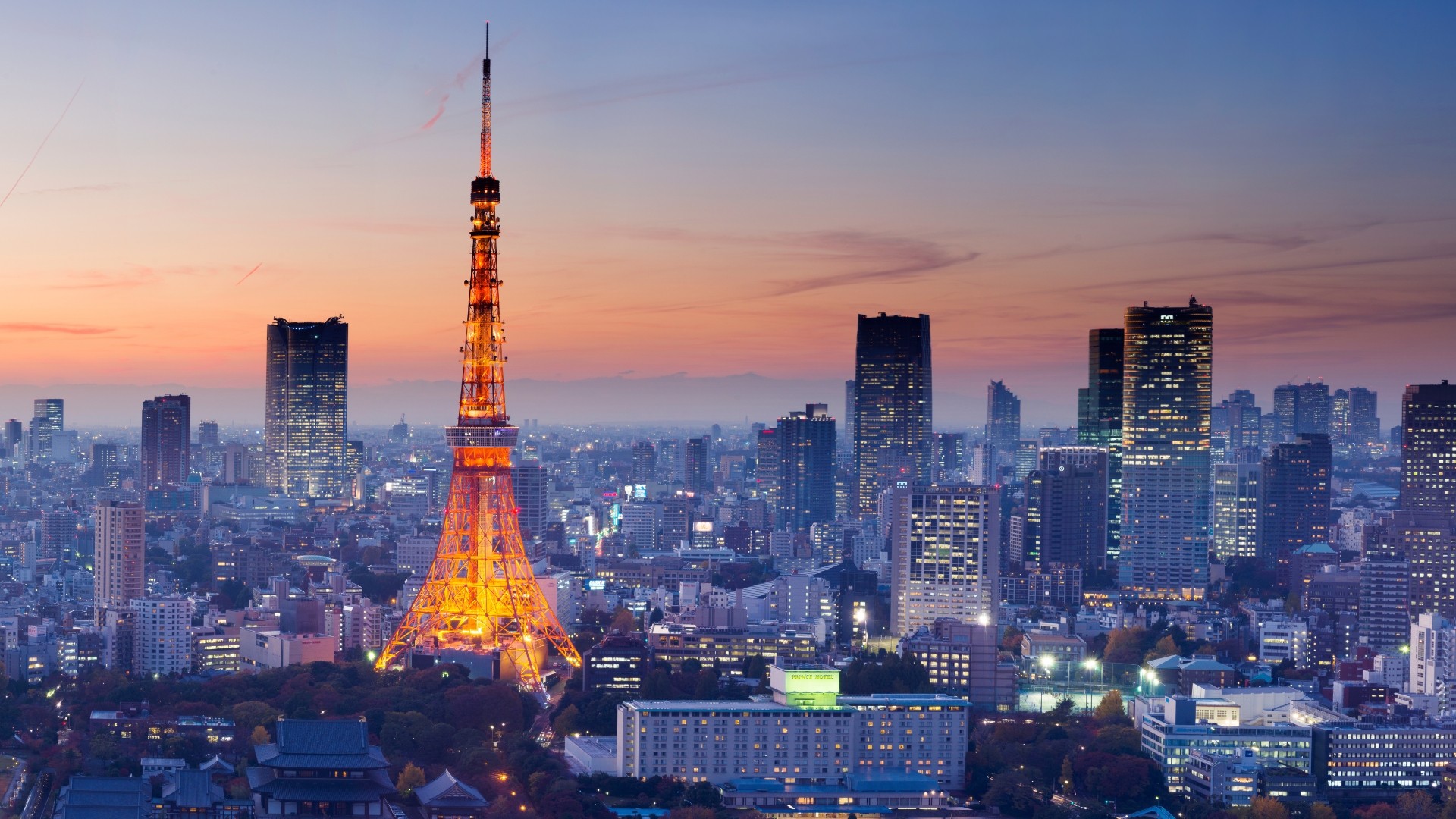 Tokyo Tower lit up at dusk among the skyscrapers of Tokyo, Japan